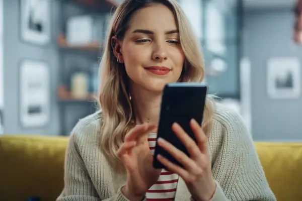 Nő a kanapén a telefonján foglal időpontot